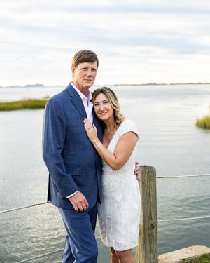 Romantic coastal engagement photos with couple posing on wooden dock by waterfront.