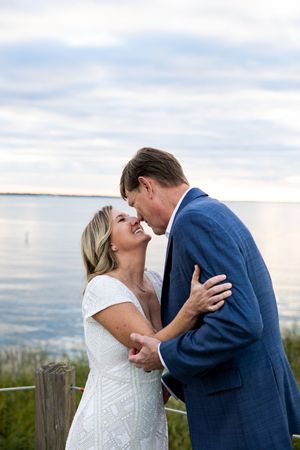 A romantic couple shares intimate moments during their wedding photoshoot against a scenic coastal backdrop.