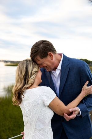 A romantic couple shares an intimate dance pose outdoors against a natural backdrop.