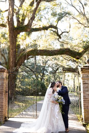 Romantic wedding moment captured in a series of photos under Spanish moss draped trees at a brick entrance gate.