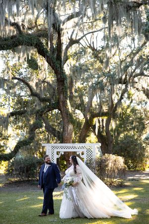 Wedding couple poses for romantic photos under Spanish moss-draped oak trees at sunset in a Southern garden setting.