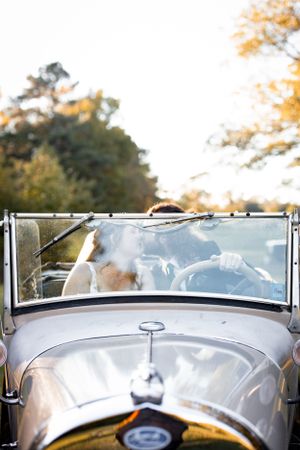 Top-down view of a classic vintage car's front windshield and silver hood during a wedding photoshoot.