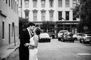 Romantic moment between newlyweds on a city street with classic architecture in the background.