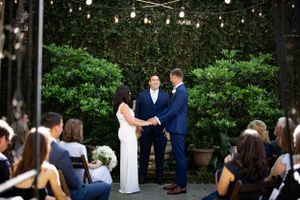 An outdoor wedding ceremony under string lights with greenery backdrop.