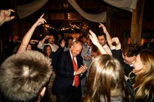 People celebrating and dancing at an indoor event venue with draped fabric decor and lighting.