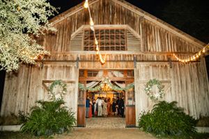 Rustic wooden barn venue illuminated at night with string lights and floral decorations for a wedding celebration.