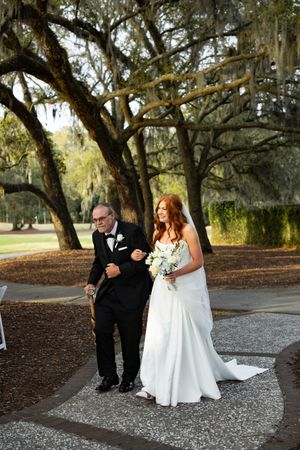 A couple shares a special moment under Spanish moss-draped oak trees during an outdoor wedding ceremony.
