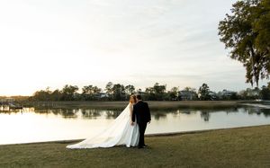 A serene lakeside wedding ceremony setup with white chairs and an arch overlooking the tranquil water at sunset.