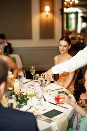 Champagne being poured at an elegant wedding reception dinner table.