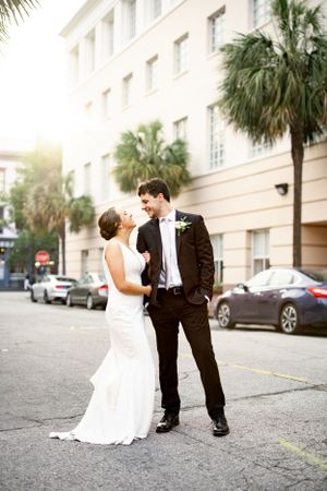 A romantic wedding portrait in front of a historic building with palm trees.