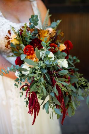 Vibrant autumn bridal bouquet with burgundy amaranthus, yellow roses, red blooms and eucalyptus greenery.