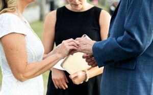 Close-up view of hands exchanging rings during an intimate outdoor ceremony.