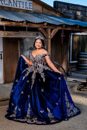 Beautiful royal blue ballgown with silver embellishments shown in front of vintage western storefronts.