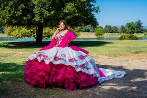 Dramatic quinceañera dress with magenta ruffles and white embroidery in park setting. van nuys.