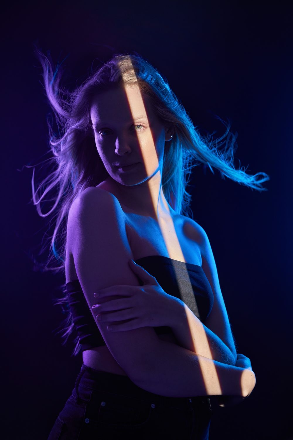 Dramatic portrait with purple and blue lighting effects highlighting a pole dancer in motion.
