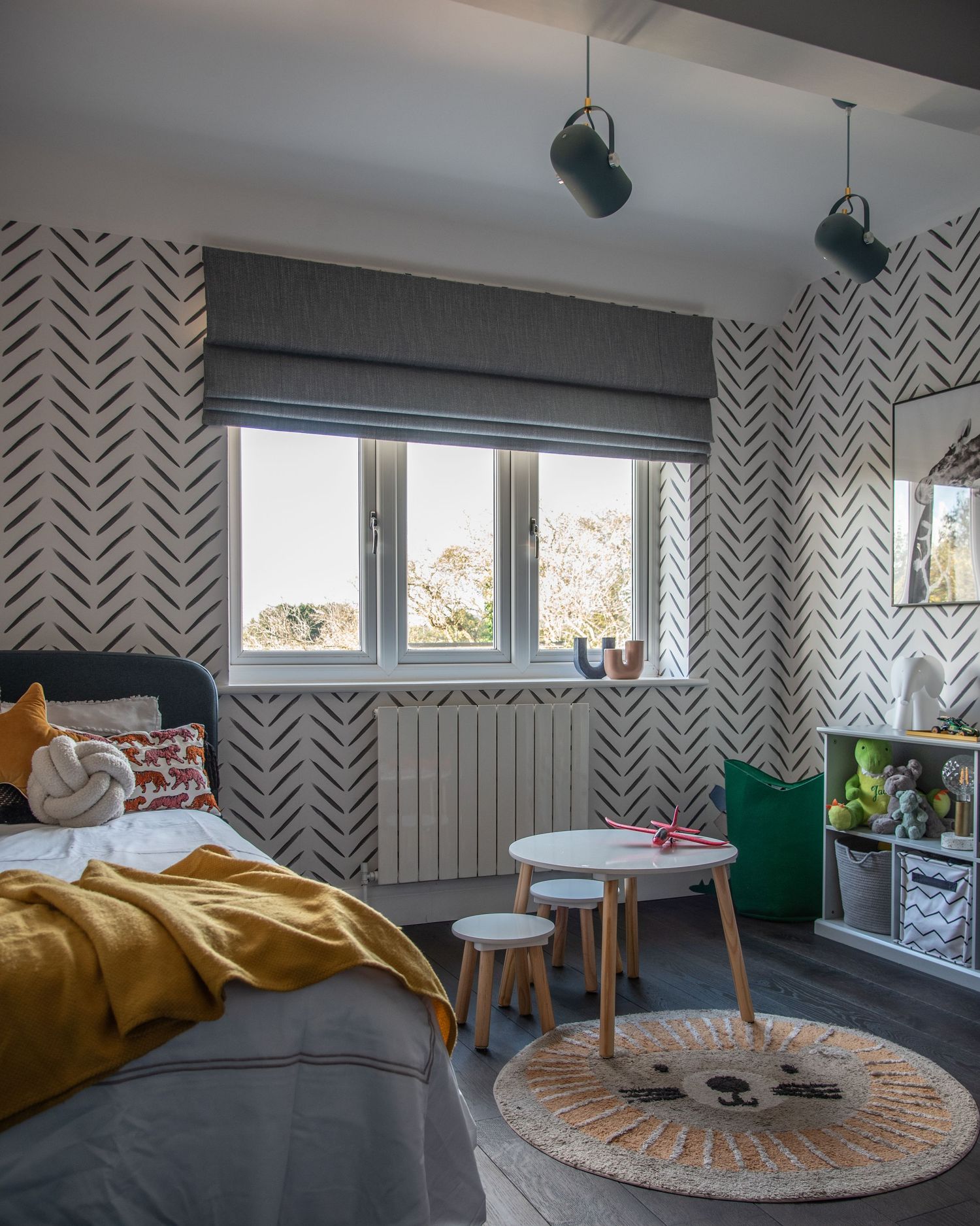 Modern bedroom with geometric herringbone pattern wallpaper, grey window shade, and yellow bedding features stylish lighting.