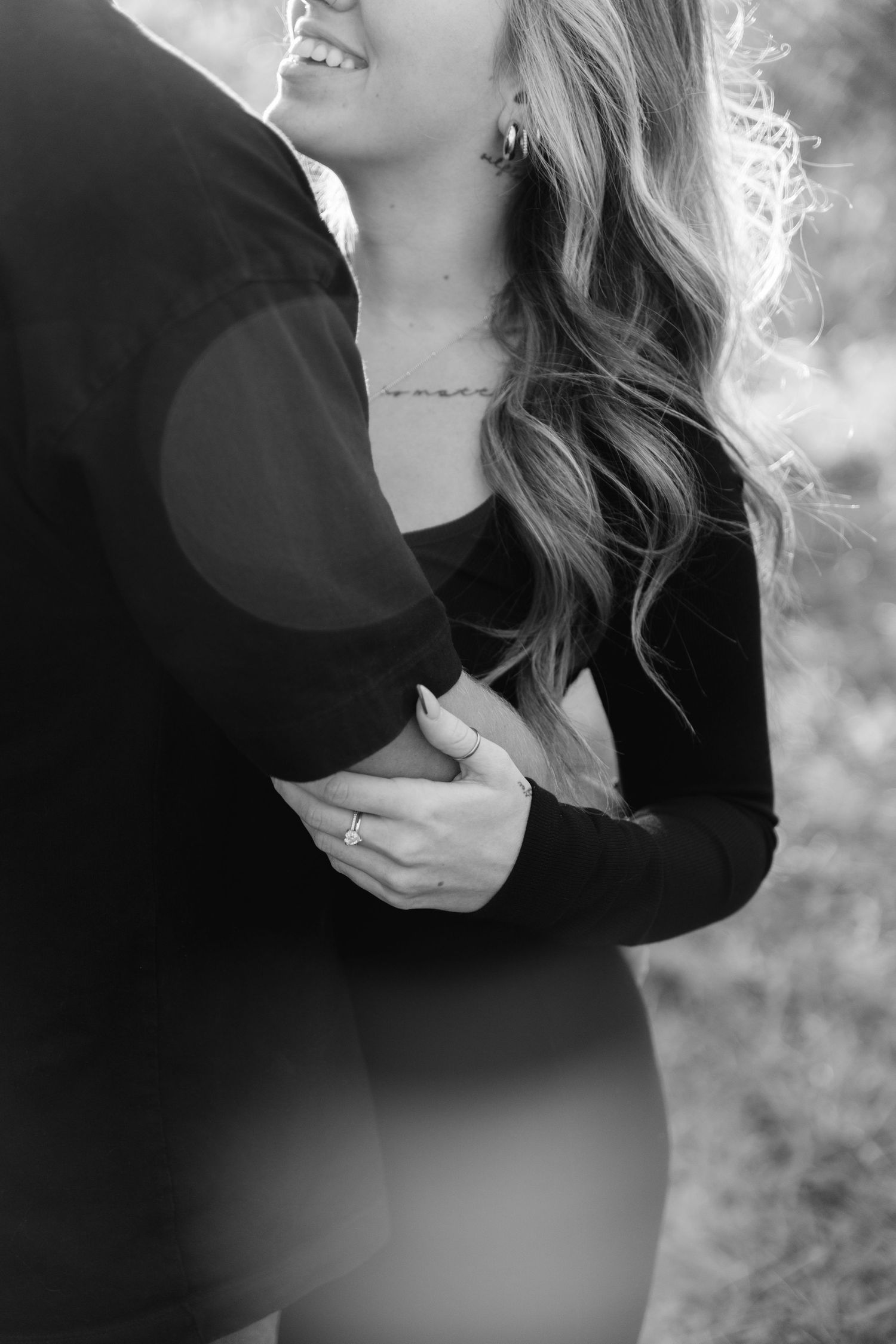 A romantic black and white photograph showing an intimate embrace between a couple in formal attire.