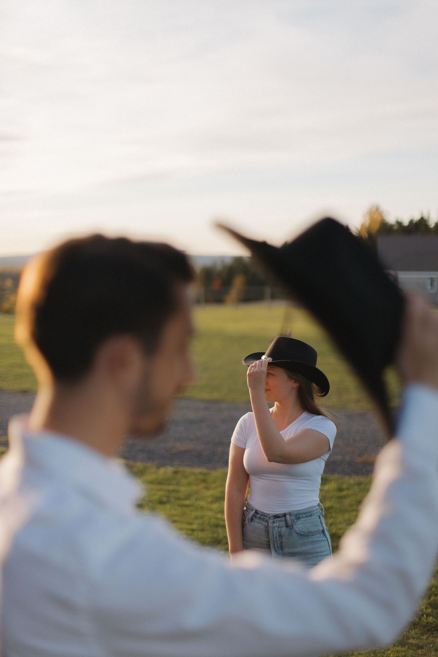 People in black cowboy hats and western outfits gather outdoors during what appears to be golden hour.