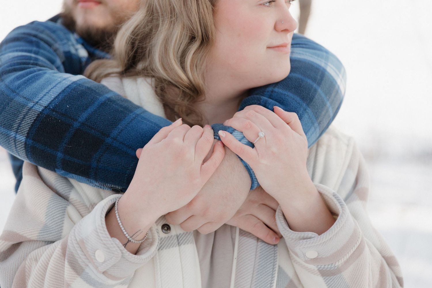 A close-up shot of a couple embracing with clasped hands, wearing a white sweater and blue denim shirt.
