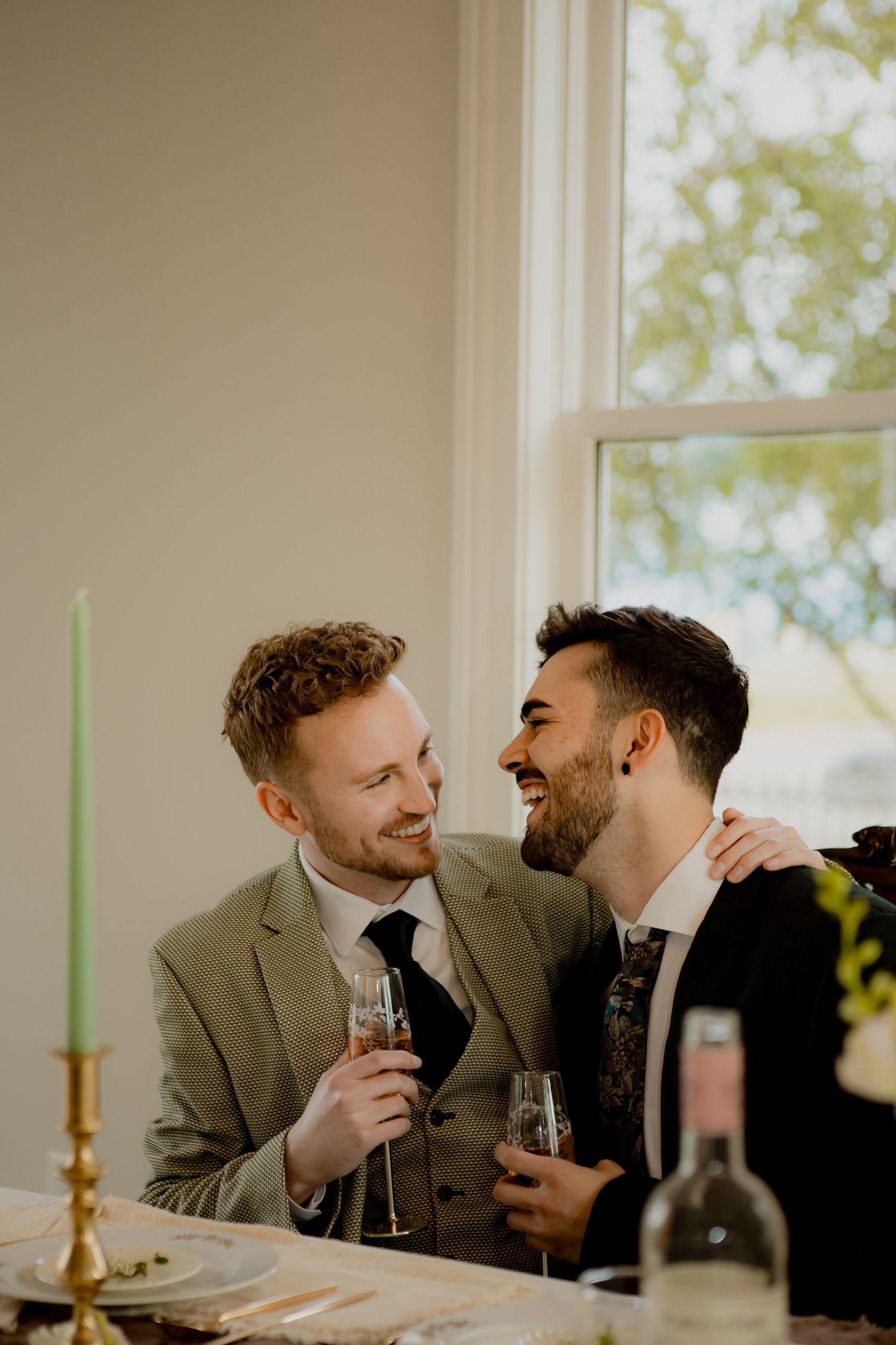Two celebrants sharing champagne and laughter at an elegant indoor reception.