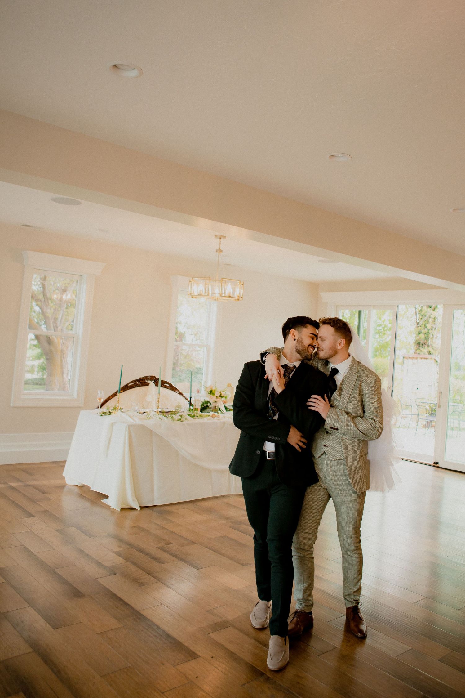 Couple sharing intimate moment during reception in bright, modern venue with hardwood floors.