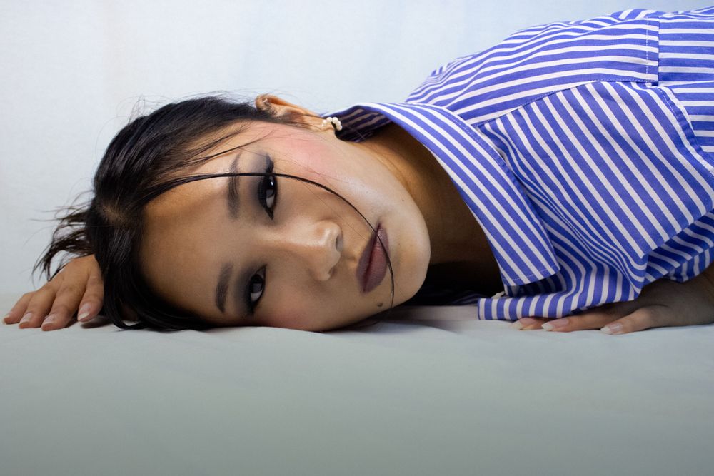 Portrait of person lying down wearing blue and white striped shirt.