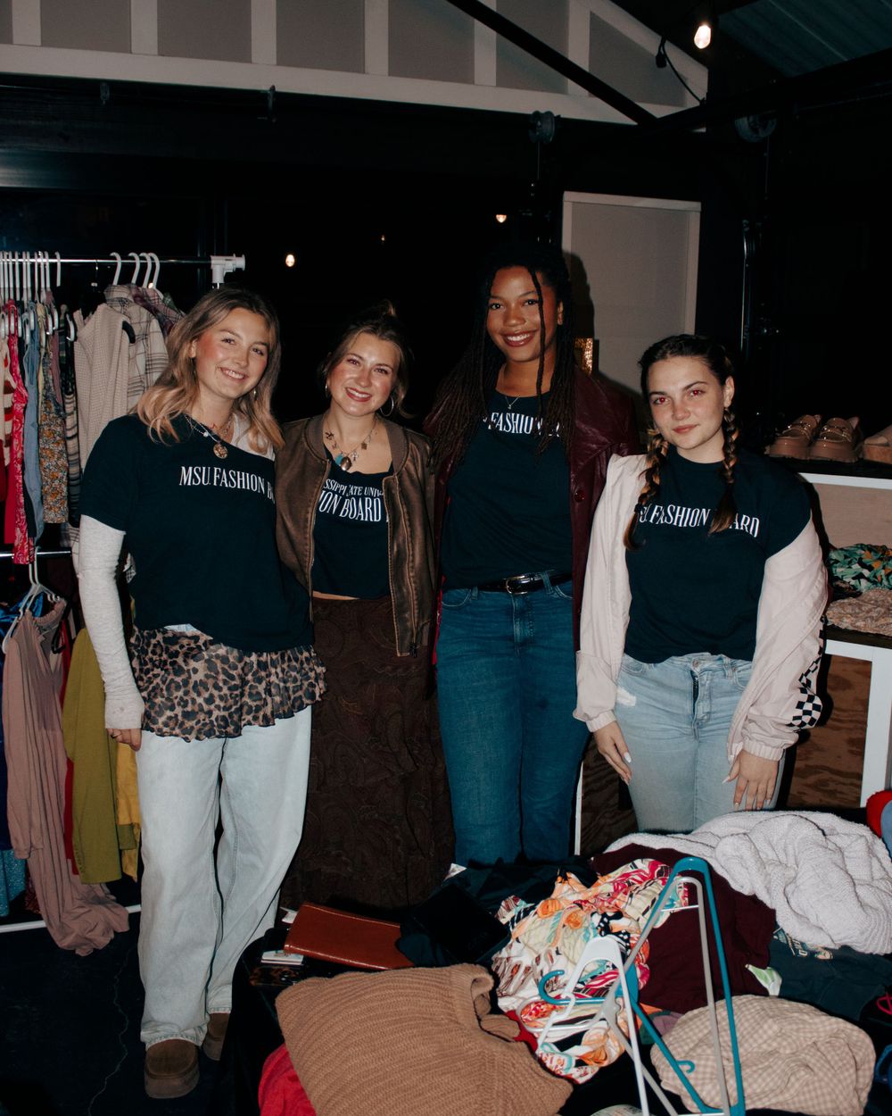 Four people in matching black t-shirts pose together at a vendor pop up event.