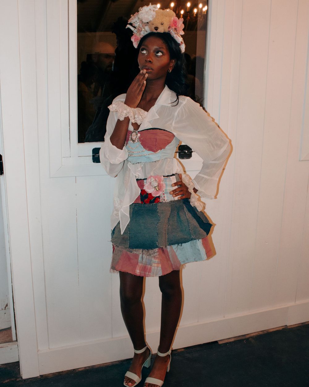 Model poses in a layered ruffle dress with blue skirt and white top.