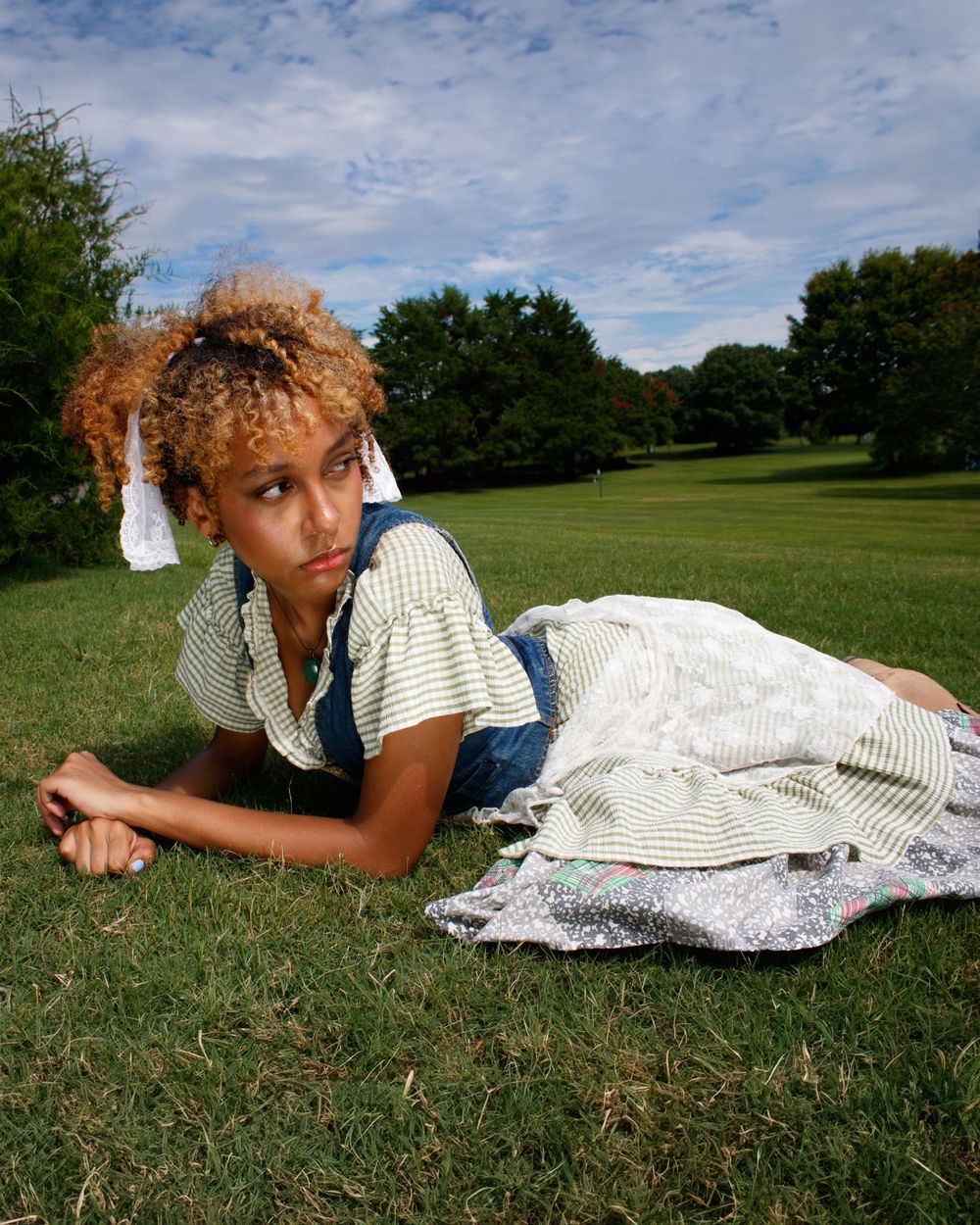 Outdoor portrait on grass featuring cottage-core style clothing and natural scenery.