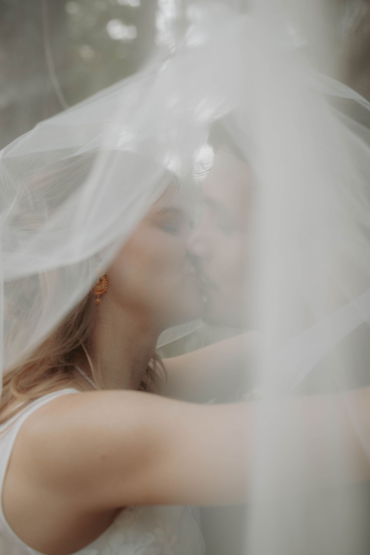 Ethereal bridal portrait with flowing white veil creating a dreamy effect.