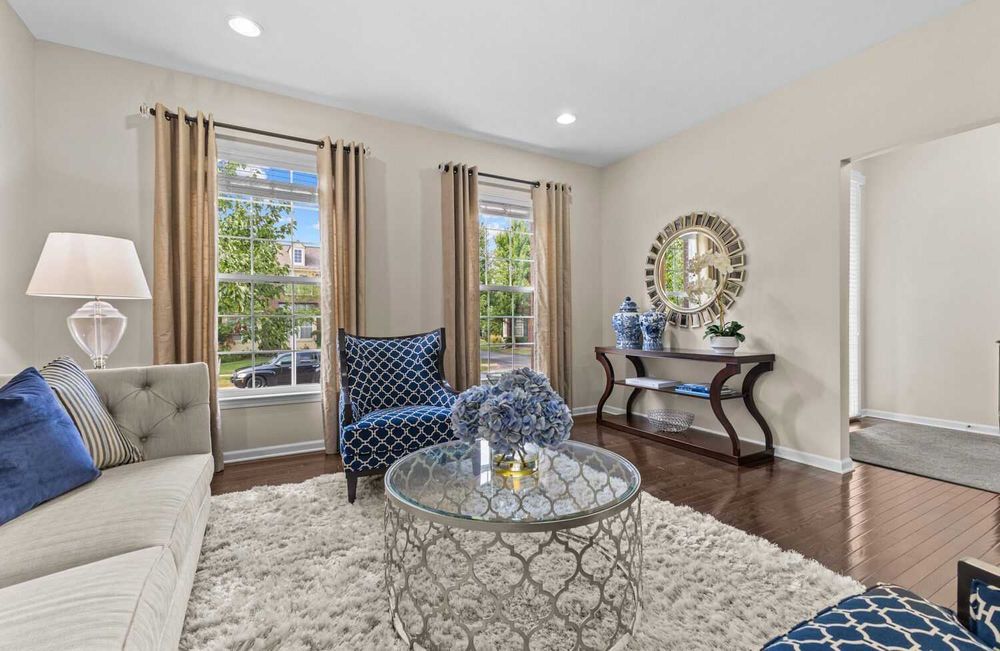 Stylish living room with blue accent chairs, shag rug, round coffee table, and large windows.