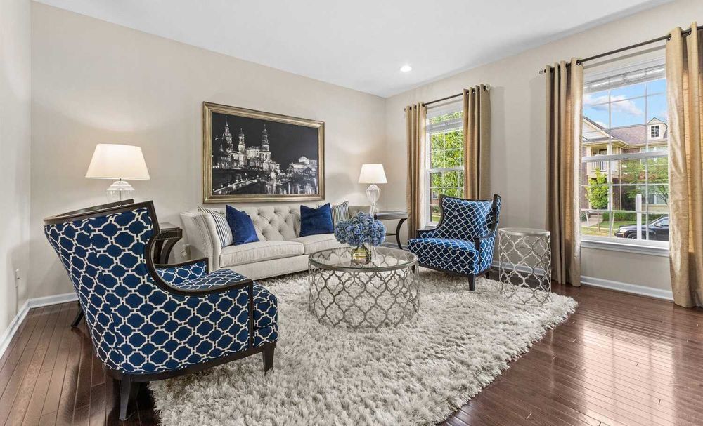 Sophisticated living room featuring blue patterned chairs, tufted sofa, shag rug, and artwork.