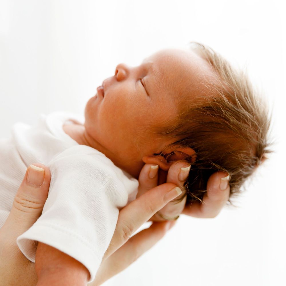 A serene newborn portrait in warm tones against a white background.