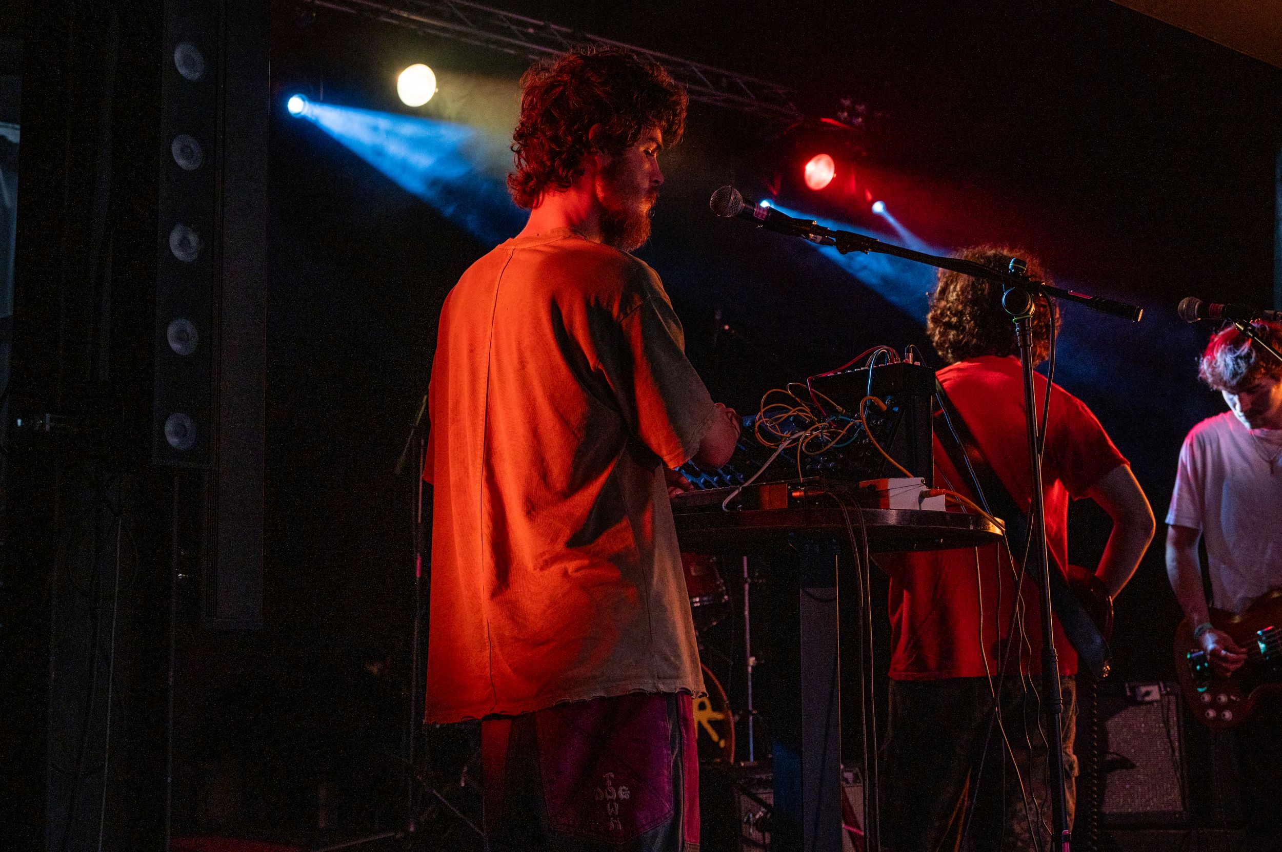 Band members playing instruments under vibrant red and blue stage lights.