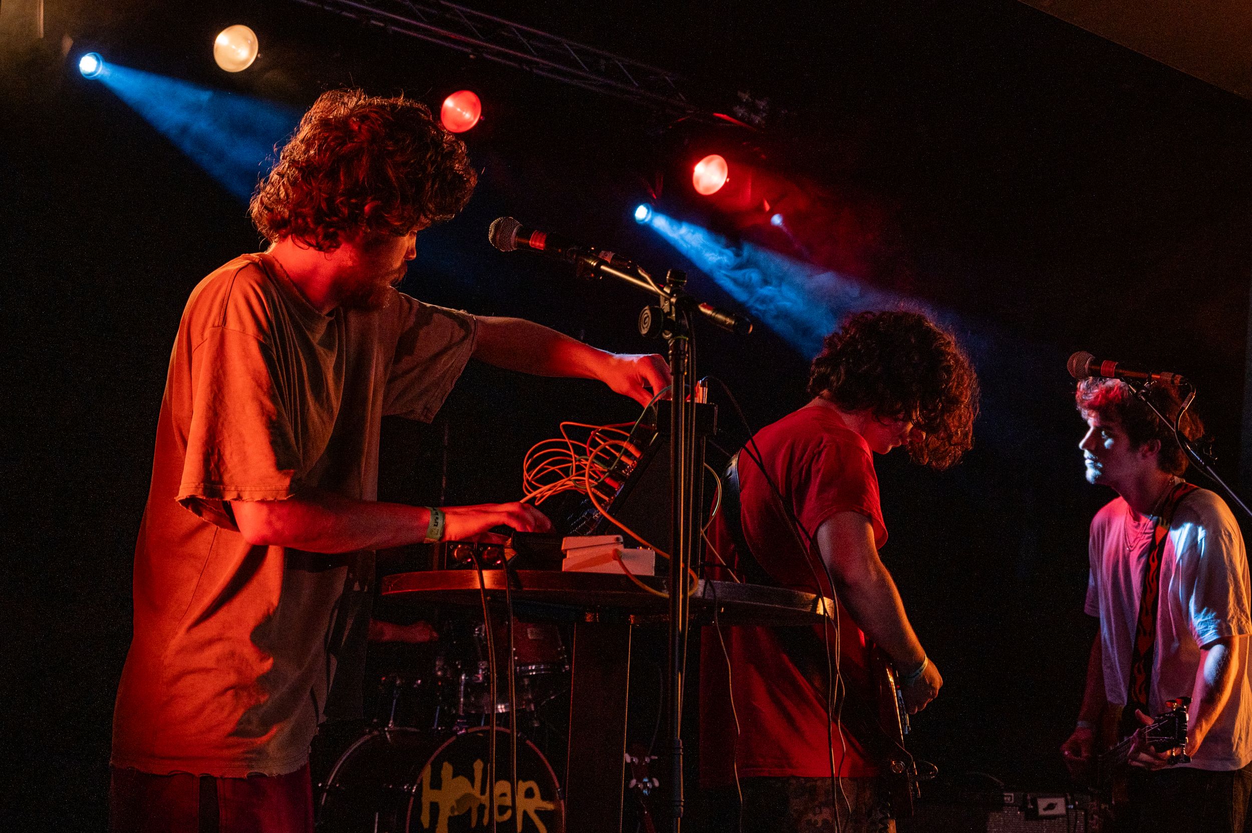 Band performing live on stage with dramatic red and blue theatrical lighting.