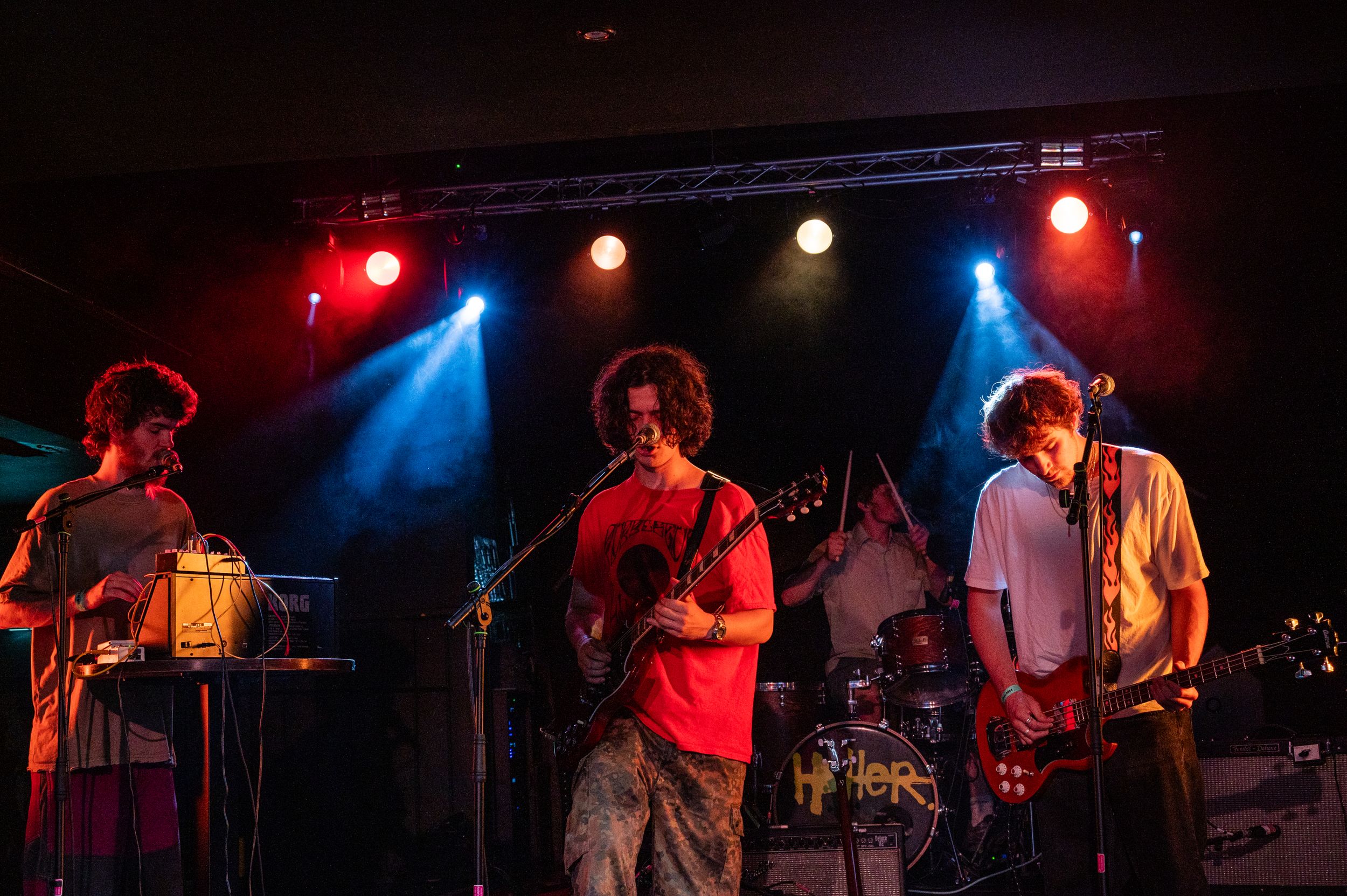 Band performs on stage with dramatic red and blue lighting creating an energetic concert atmosphere.
