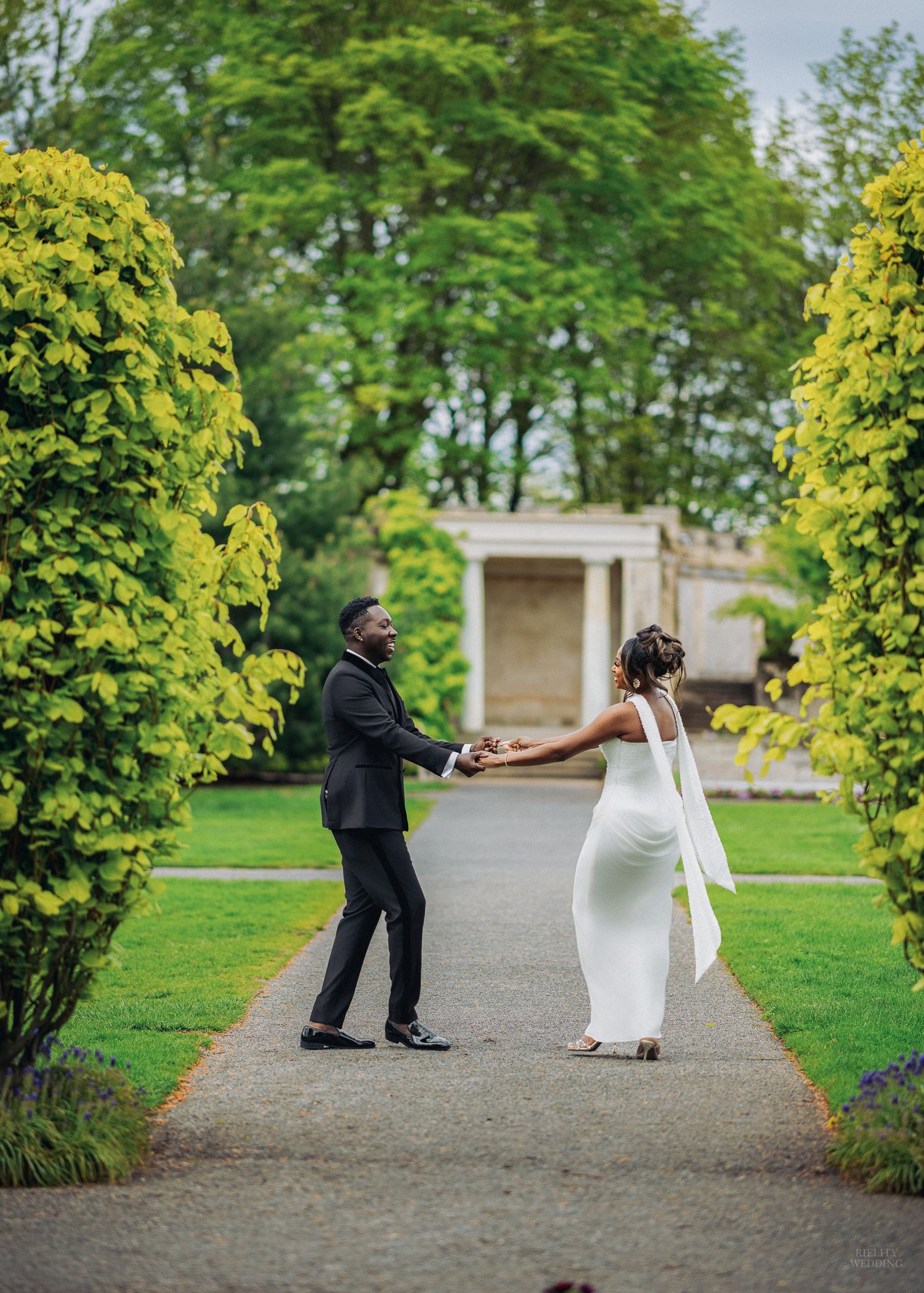 A romantic wedding moment with a couple in white attire sharing a kiss while holding a blue and white bouquet.
