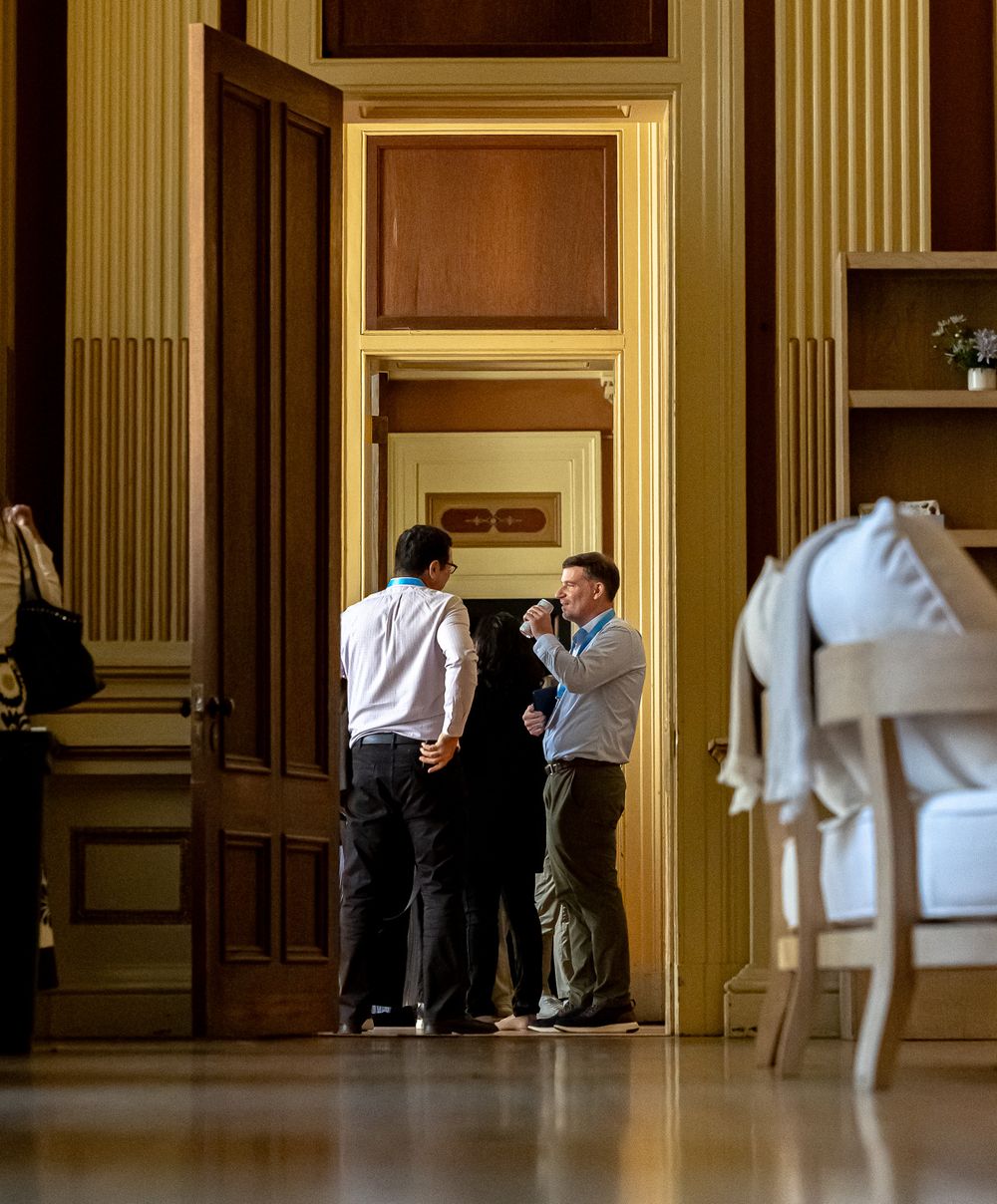 People having a conversation in an elegant hallway with classical architectural details.