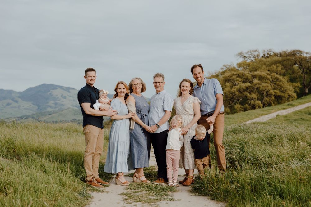 Group portrait of family members on hiking trail with mountains in background.