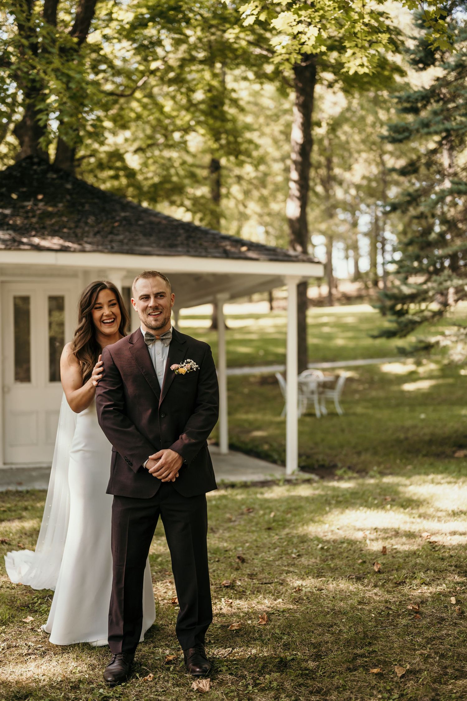 Couple shares a joyful moment together outdoors by a white building on their wedding day.