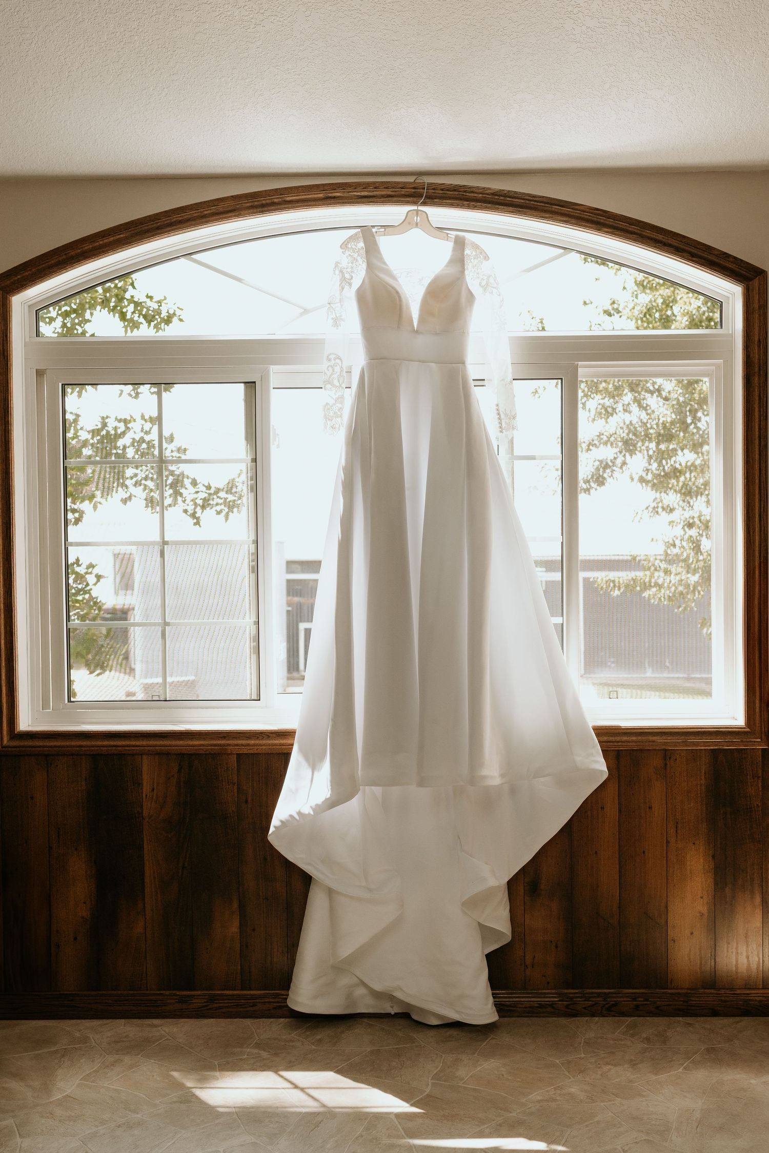A series of sepia-toned photographs showing a white wedding dress hanging in front of arched windows with natural light.
