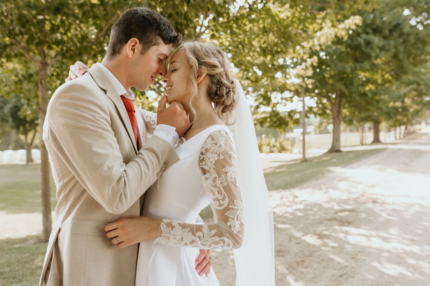 A romantic couple shares tender moments in a sunlit outdoor setting with trees in the background.