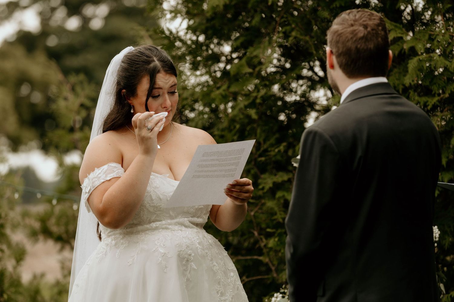 Emotional wedding ceremony moment between couple exchanging vows outdoors in a garden setting.