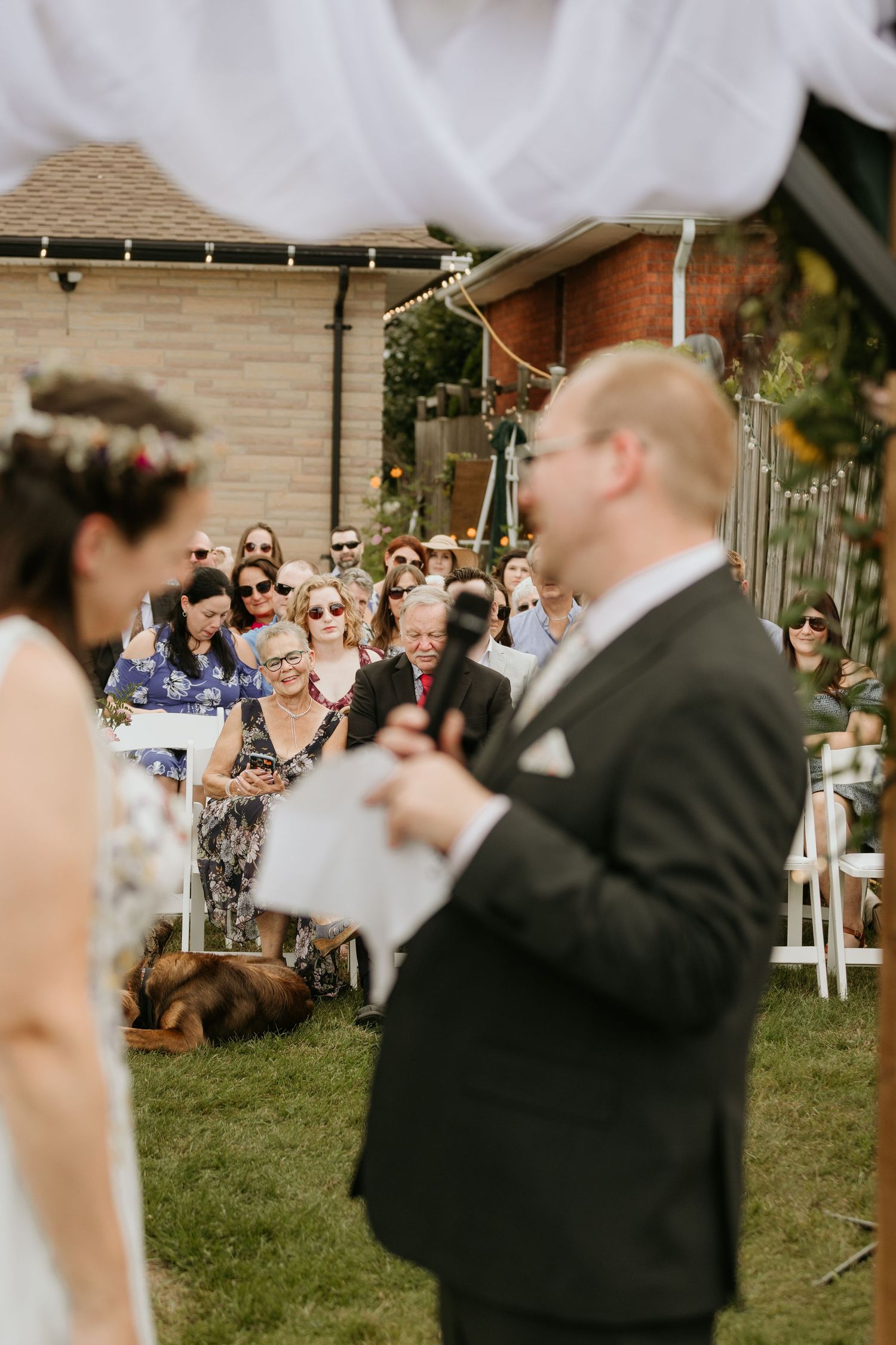 Wedding guests enjoy blowing bubbles during an outdoor ceremony celebration on a sunny day.