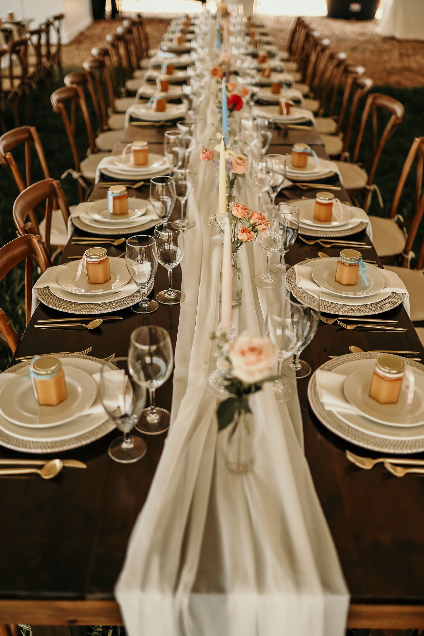 An elegant table setting with white linens, roses and place settings for a formal dinner event.