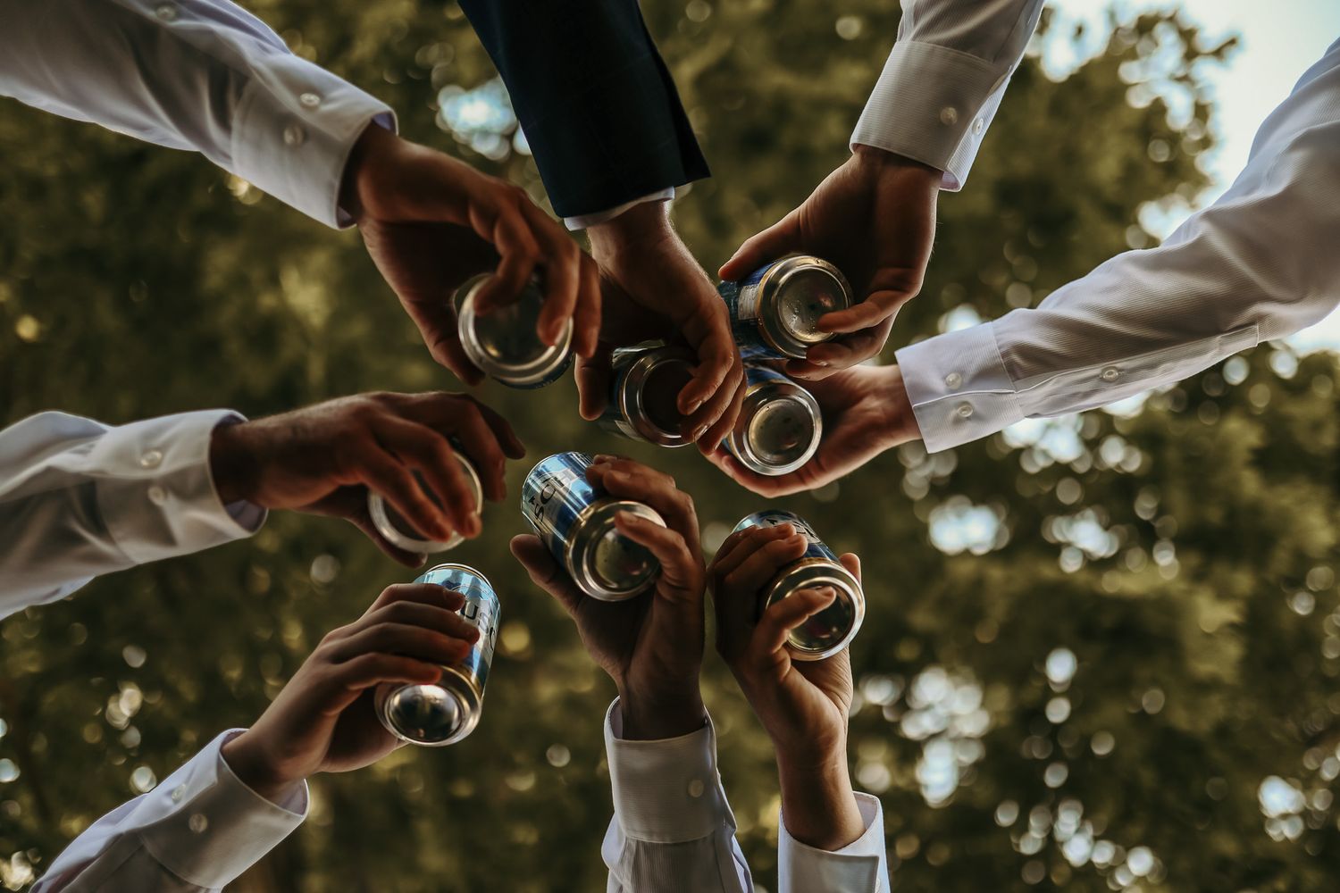 Circle of groomsmen's hands showing their wedding rings in an artistic overhead shot.