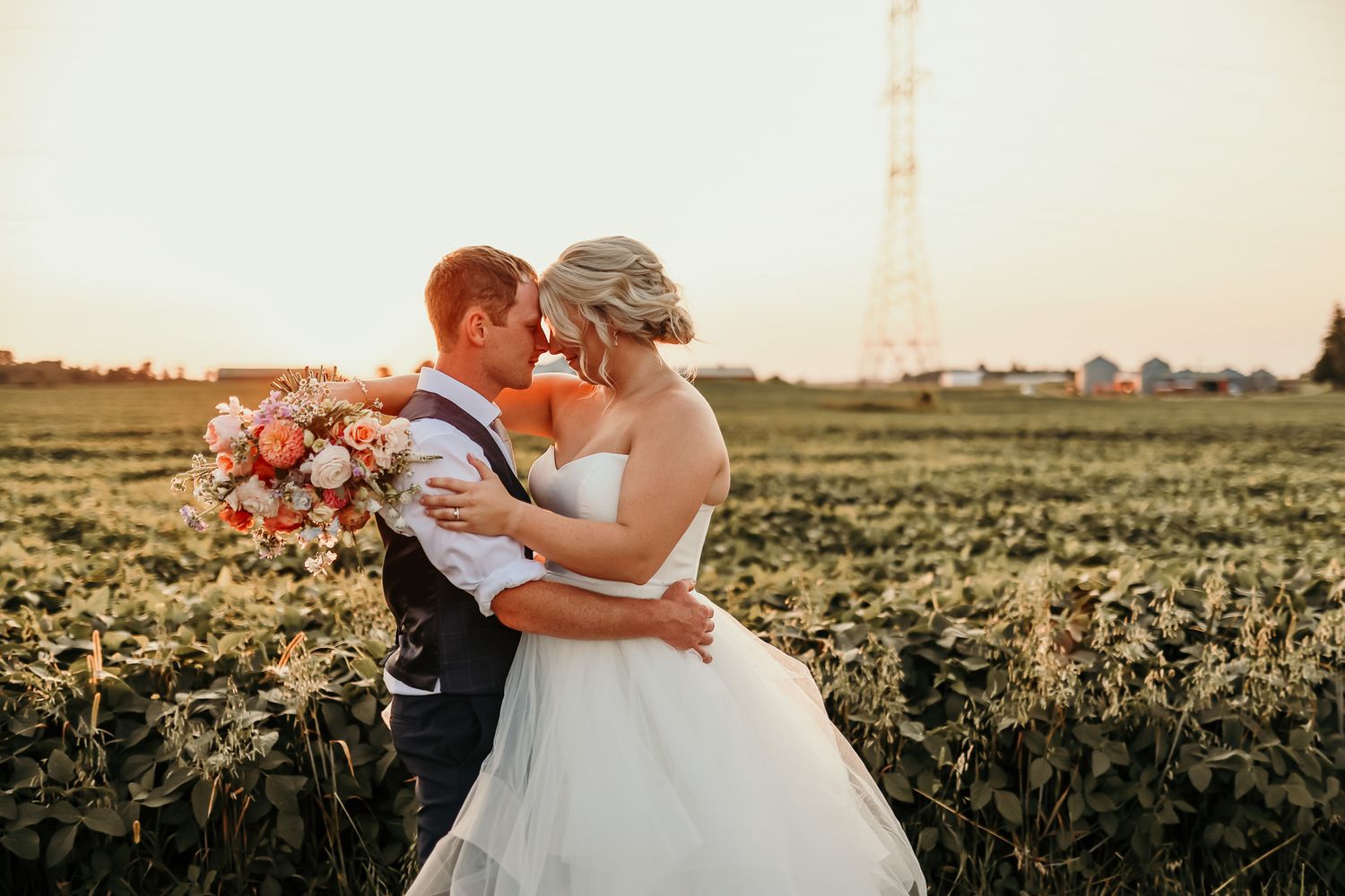 Romantic sunset wedding portrait in sunflower field with soft golden light.