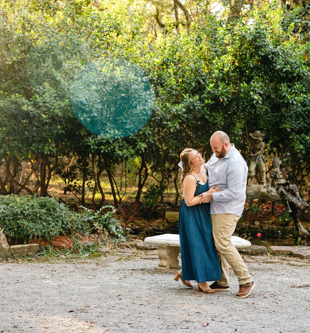 A couple dances together on a garden path surrounded by lush greenery.