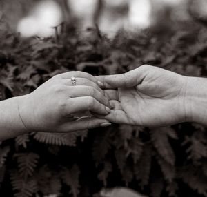 Close-up black and white photo of hands reaching towards each other against a blurred background.