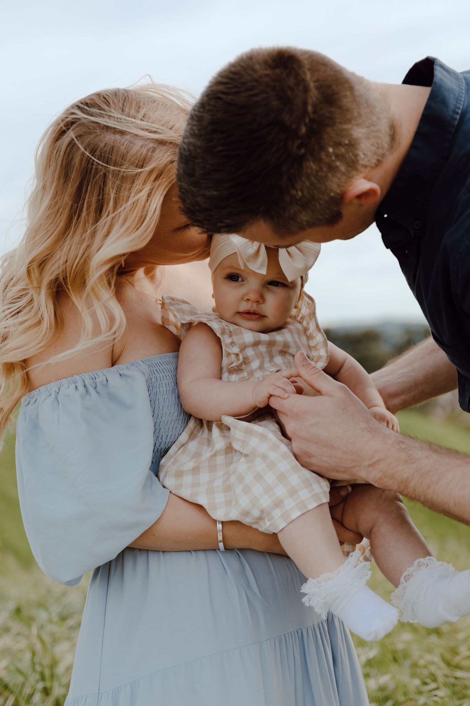 A tender family moment captured in soft natural light outdoors.